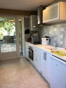 a kitchen with white cabinets and a sliding glass door at Olive et Pomme in Bretteville