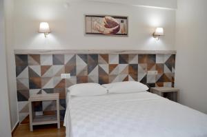 1 dormitorio con cama blanca y pared geométrica en Megas Hotel, en Ayvalık