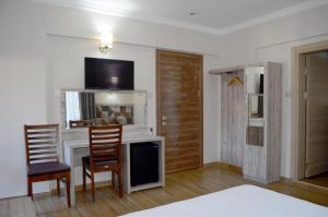 a living room with a desk with a tv and two chairs at Megas Hotel in Ayvalık