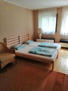 a bedroom with a large bed and a chair at Szőlősi Diófa Vendégház in Balatonszőlős
