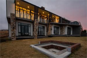 a large house with a fire pit in front of it at Highland Gate House 1023 in Dullstroom