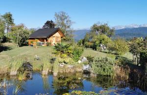 a log cabin with a pond in front of it at Au petit chalet avec son SPA - Escapade en amoureux ! in Cruet