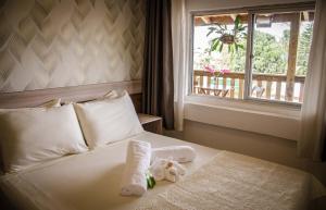 a bed with two stuffed animals on it with a window at Hotel Costa Praia in Piçarras