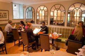 a group of people sitting at tables in a restaurant at The Parliament House Hotel in Edinburgh