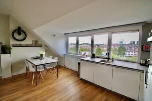 cocina y comedor con mesa y ventanas en Beautiful penthouse near Rai and centre en Ámsterdam