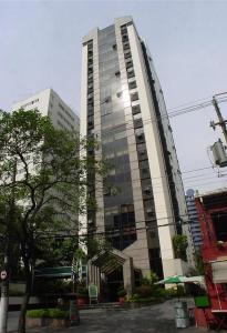 un grand bâtiment avec un arbre devant lui dans l'établissement Newciti Flat Itaim Bibi, à São Paulo