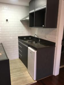 - une cuisine avec des placards noirs et un évier dans l'établissement Newciti Flat Itaim Bibi, à São Paulo