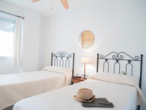kapelusz siedzący na dwóch łóżkach w pokoju w obiekcie Apartamentos Irta Playa w mieście Alcossebre