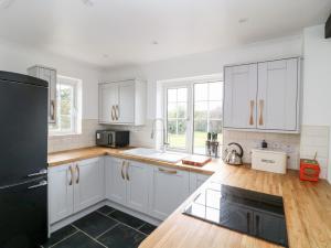 a kitchen with white cabinets and a black refrigerator at Summercourt in Launceston