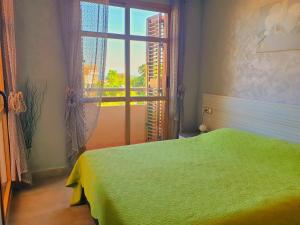 a bedroom with a green bed and a window at Casa Cerezos in Cala de Finestrat