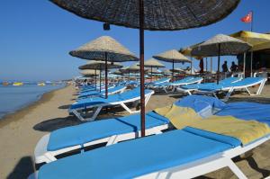 un montón de sillas de playa y sombrillas en una playa en Megas Hotel, en Ayvalık