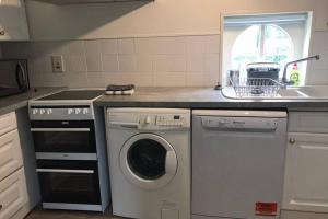 uma cozinha com uma máquina de lavar roupa e um lavatório em Coach House em Weedon