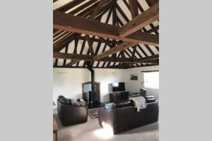 a living room with leather furniture and a wooden ceiling at Coach House in Weedon