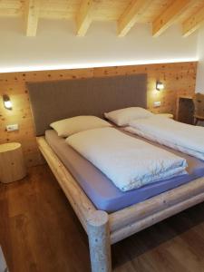 two twin beds in a room with wooden walls at Chalet Niederhaushof in Ultimo