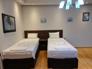 two beds in a room with white walls and wood floors at City Center Apartments in Strumica