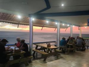 a group of people sitting at tables looking at the ocean at Blue View Apartments in Sabana Westpunt