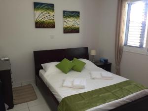 a bedroom with a bed with white sheets and green pillows at Anarita Townhouse in Anarita