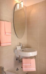 ein Badezimmer mit einem Waschbecken, einem Spiegel und rosa Handtüchern in der Unterkunft Hotel Panorama Ristorante ***S in Torri del Benaco