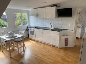 cocina con armarios blancos, mesa y TV en DG Wohnung mit separatem Eingang nahe Düsseldorf, en Meerbusch