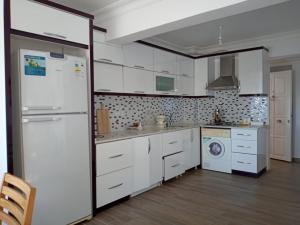 a kitchen with white cabinets and a white refrigerator at Heybe Apart in Kaş