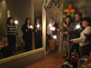 a group of people standing in front of a mirror holding sparklers at Happy Taipei Hostel - Share House in Taipei