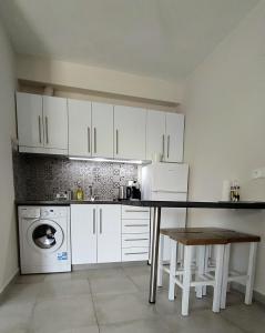 a kitchen with white cabinets and a table and a dishwasher at Happy Anchor Apartments in Kallithea Halkidikis