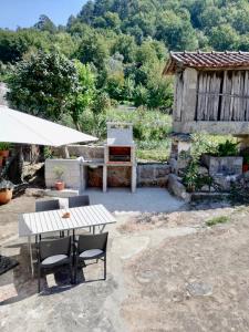 a patio with a table and chairs and a grill at Casa da Laija - Vistas rio, campo e montanha in Cova