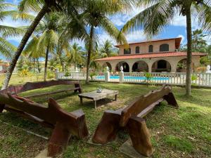 a park with benches and a building with palm trees at Pousada Aqualuna - São Miguel dos Milagres in São Miguel dos Milagres