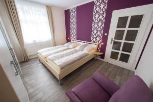 une chambre avec un lit et un mur violet dans l'établissement Weitblick-Ferienwohnung, à Eisenach