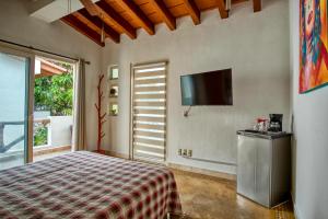 a bedroom with a bed and a flat screen tv at Hacienda Alemana Hotel Boutique in Puerto Vallarta