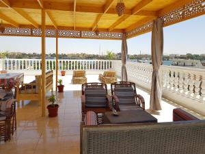 eine Veranda mit Stühlen und Tischen auf dem Balkon in der Unterkunft Luxor VIP Apartments in Luxor