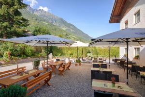 um restaurante com mesas e guarda-sóis com montanhas ao fundo em Goldene Rose em Naturno