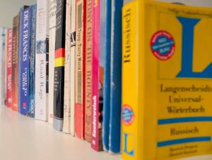 a row of books on a shelf at Red Nose Hostel with Self-Check In in Rīga