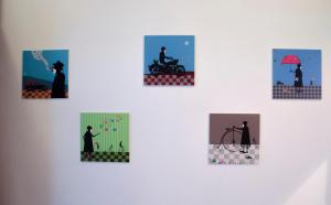 a group of paintings on a white wall at Red Nose Hostel with Self-Check In in Riga