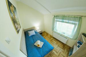 um pequeno quarto com uma cama azul e uma janela em Sunflower em Sombor
