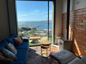 a living room with a blue couch and a large window at Douro Marina Studios in Vila Nova de Gaia