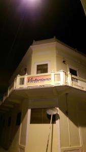 a white building with a balcony with a sign on it at Hotel Victoriano in San Felipe de Puerto Plata