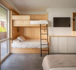 Habitación pequeña con literas y TV. en Cristina Enea Rooms, en San Sebastián