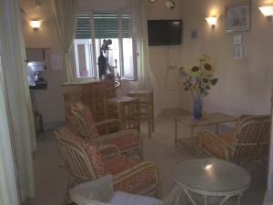 uma sala de estar com cadeiras, uma mesa e uma televisão em Hotel Magda em Rimini