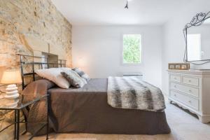 1 dormitorio con cama y pared de piedra en Mas des Genêts, en Manosque