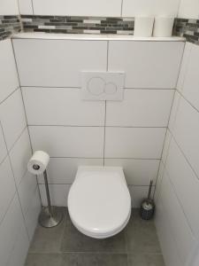 La salle de bains est pourvue de toilettes blanches et d'un mur carrelé blanc. dans l'établissement 6 personnes, neuf & cosy, centre - gare, à Mulhouse