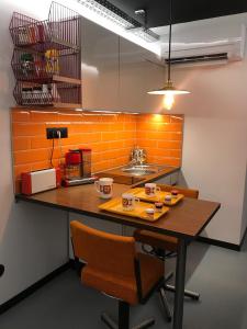 an orange kitchen with a wooden table and chairs at la kischte vintage in Colmar