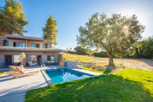 a house with a swimming pool and a tree at Olive White Villa in Hanioti