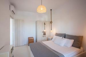 a bedroom with a bed with white sheets and a lamp at Olive White Villa in Hanioti +36 photos