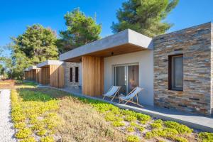 a brick house with two chairs on the side of it at Olive White Villa in Hanioti