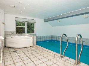 a bathroom with a tub and a swimming pool at 10 person holiday home in Henne in Henne Strand