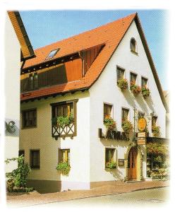 ein weißes Gebäude mit rotem Dach und Blumenkästen in der Unterkunft Gasthof Lamm in Beilstein