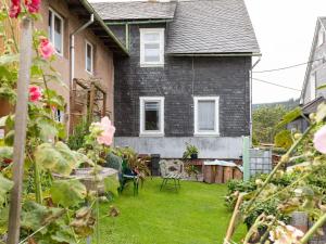a house with a yard with chairs and flowers at Cozy Apartment in Altenfeld with Garden in Altenfeld