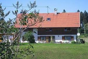 ein großes Haus mit rotem Dach auf einem Feld in der Unterkunft Haus Hörger in Maierhöfen