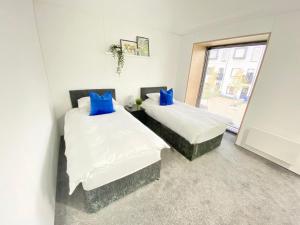 two beds with blue pillows in a room with a window at Large Townhouse 5 Beds with Two Parking Spaces - Manchester City Centre in Manchester